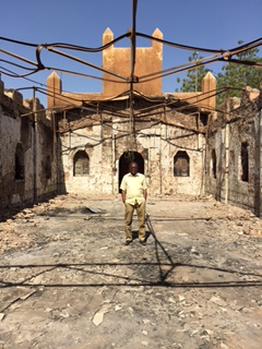 Rev. Jacques Kangindé stands alone inside the remains of his 'Roundabout' church. - World Watch Monitor